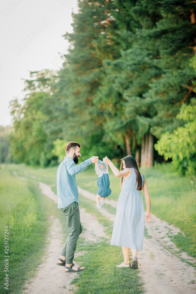 Naklejka premium Parents help their child make the first steps in life. Rear view