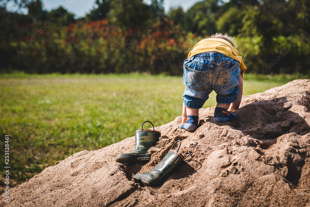 Young child bending over and playing in sand in the middle of a field. Young child bending over and playing in sand in the middle of a field.