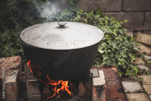 Closed black cauldron boiling on fire