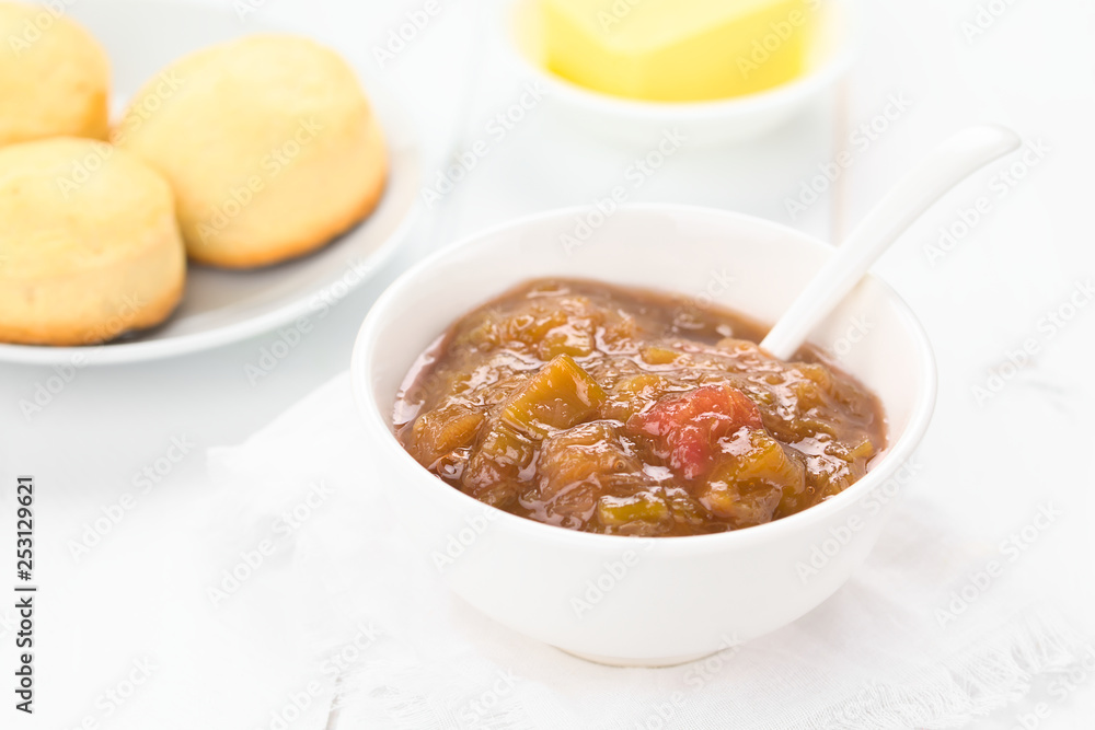 Homemade rhubarb jam in bowl with scones and butter in the back (Selective Focus, Focus in the middle of the bowl) Homemade rhubarb jam in bowl with scones and butter in the back (Selective Focus, Focus in the middle of the bowl)