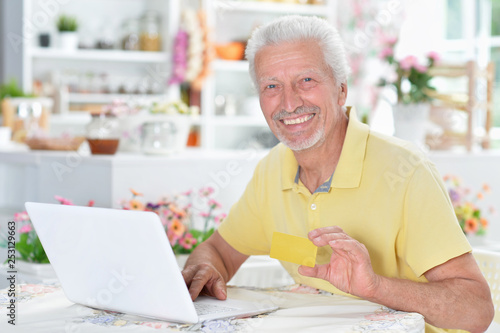 Portrait of beautiful senior man using laptop at home