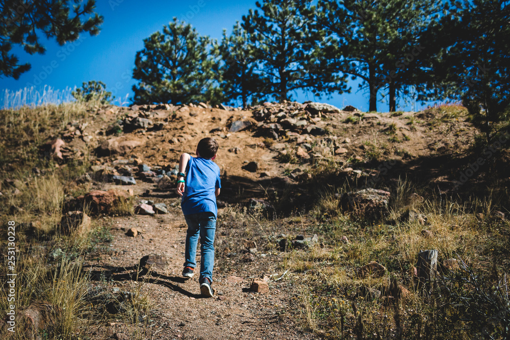 Young boy running up a mountain with rocks and trees. Young boy running up a mountain with rocks and trees.
