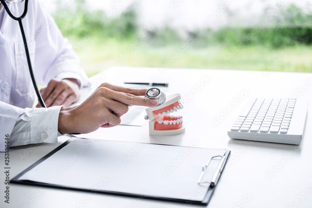 Fototapeta premium Male doctor or dentist checking teeth disease in dental model and equipment used in the treatment of dental and dentistry at workplace