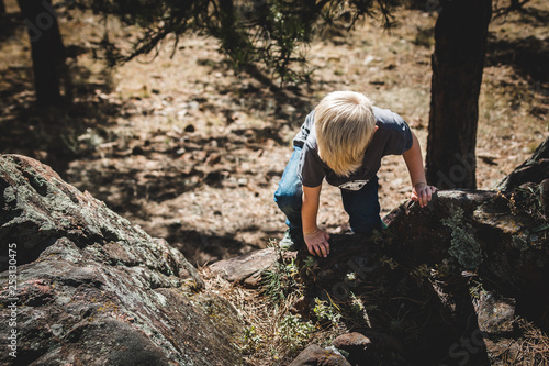 Young boy climbing rocks in the forest.