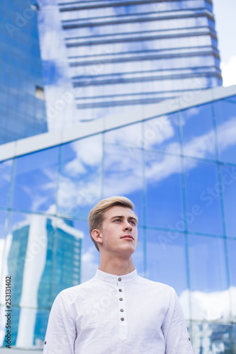Young guy on the background of the business center building in a white shirt