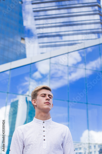 Young guy on the background of the business center building in a white shirt