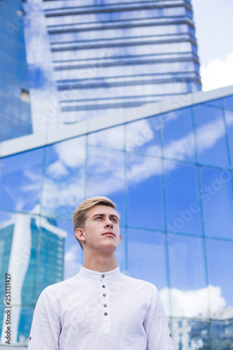 Young guy on the background of the business center building in a white shirt