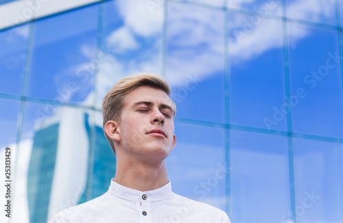 Young guy on the background of the business center building in a white shirt