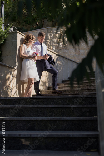 Young couple man and a woman after the wedding in a love photo session in the park on a bench.