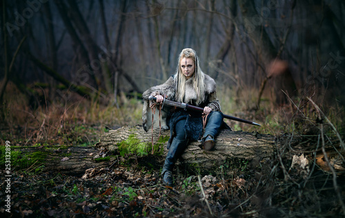 Fototapeta Mad furious viking woman warrior with a sword in her hands, in the woods
