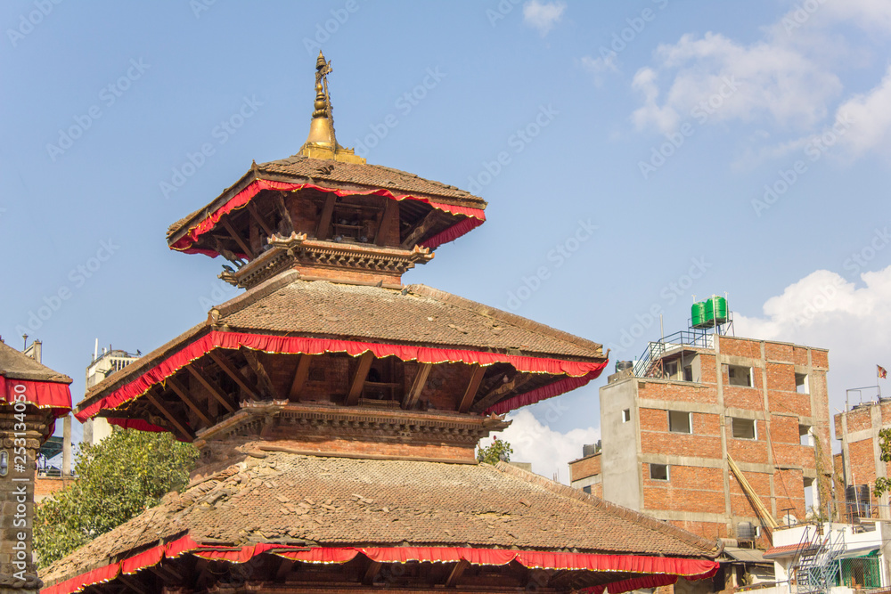 ancient asian temple pagoda against urban houses and blue sky