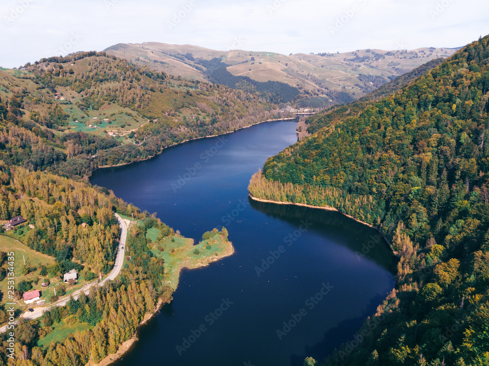 Aerial view of a green mountains and river, lake Sebes. Road for motorcyclists, near Transalpina and Sibiu, Romania. Tau Bistra. Travel concept, adventure. autumn panorama, lakeside hotel