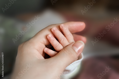 Close up baby's hand put on mom's hand. Mom nursing baby. mom and baby boy relax at home. Nursery interior. Mother breast feeding baby. Family at home. Mom's love. selected focus © Lizaveta