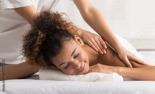 Woman enjoying shoulder massage in spa center