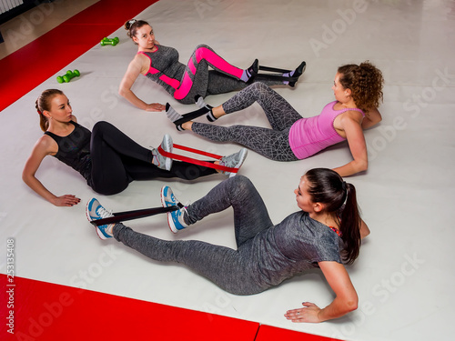 A group of girls trains the abdominal press doing fitness with the help of expander in the gym