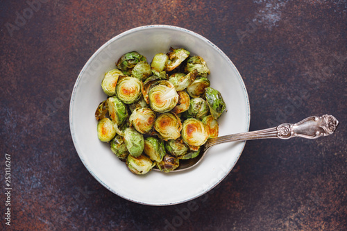 Top view of a ceramic bowl with roasted brussel sprouts on a table. The concept of healthy vegetarian eating.