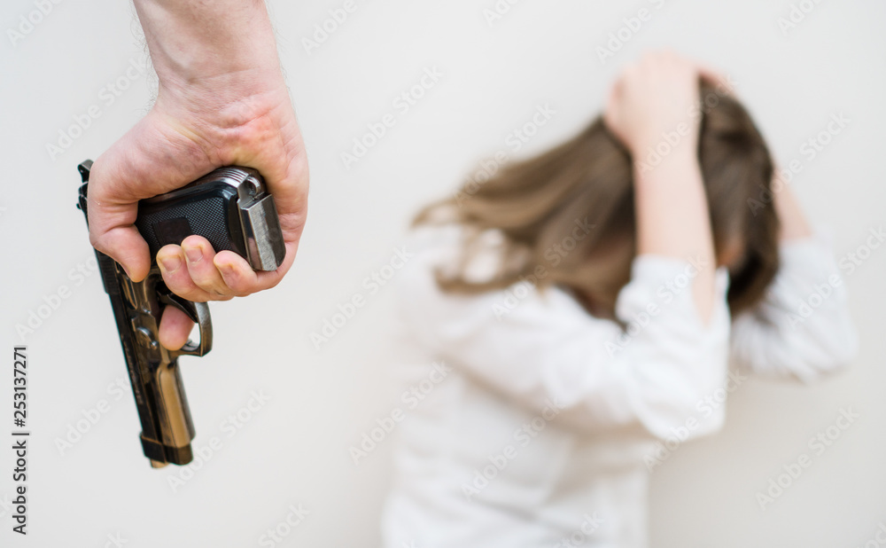 Fototapeta premium Home violence concept. Man with gun threaten woman.
