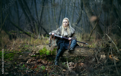 Foto Mad furious viking woman warrior with a sword in her hands, in the woods