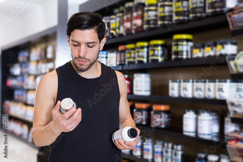 Serious young muscular man choosing  sport dietary supplements