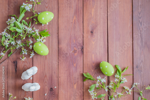 Flat lay composition with white spring flowers and easter eggs on a wooden background