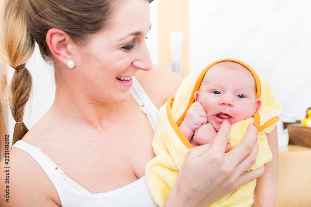 Smiling mother carrying her baby wrapped in towel Smiling mother carrying her baby wrapped in towel