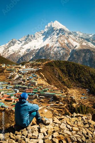 Everest trekking. The man sits and looks into the valley. Thinks and contemplates. Near the mug. Nepal. Namche Bazaar. Tourist in focus. The background is blurred