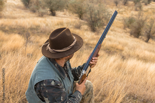 Hunter with a hat and a gun in search of prey in the steppe