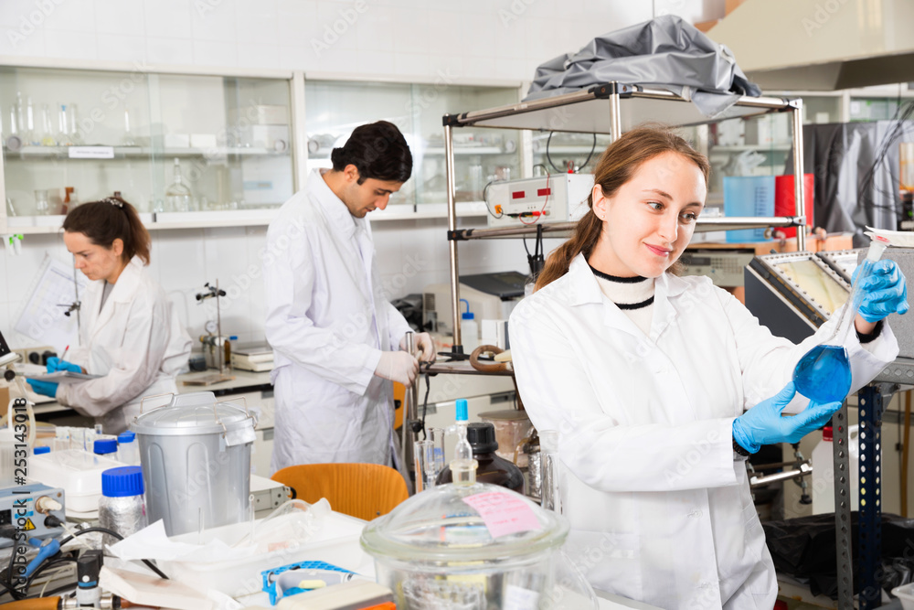 Young female lab technician working with reagents in test tubes during chemical experiment
