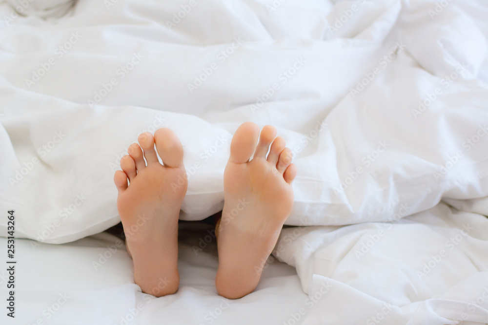 Wooman feet under blanket. Wake up in the morning. Get enough sleep concept. Wooman feet under blanket. Wake up in the morning. Get enough sleep concept.