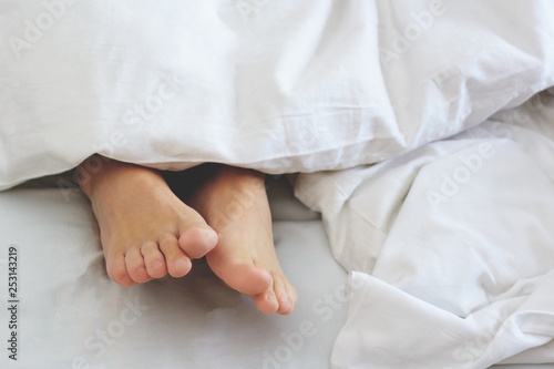 Wooman feet under blanket. Wake up in the morning. Get enough sleep concept. © Galina_lya