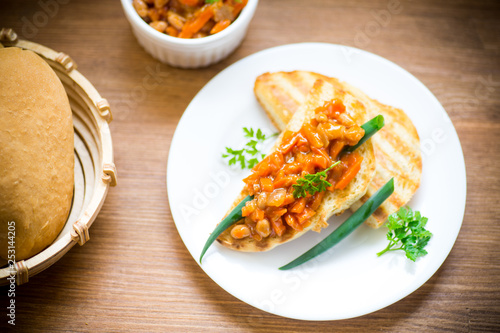 fried bread toasts with stewed beans and vegetables in a plate