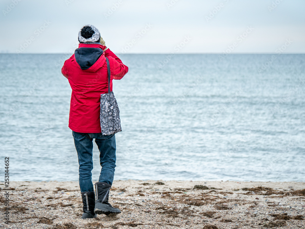 Young man on the beach wachting birds life using telescope