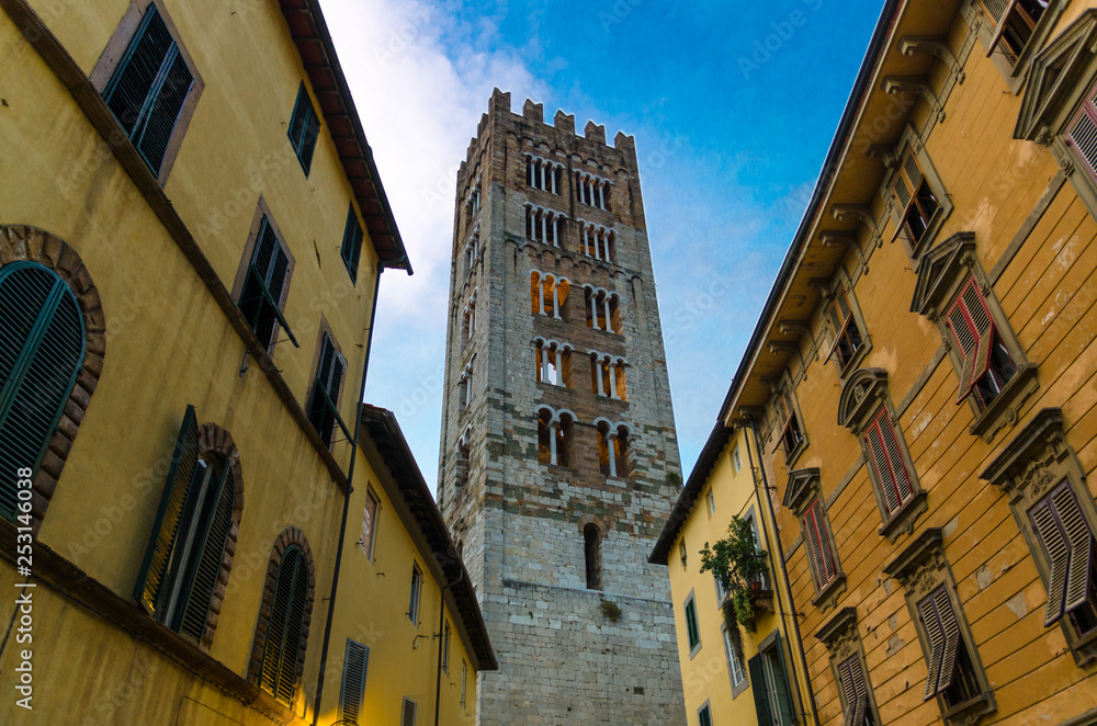 Bell tower of Chiesa di San Frediano catholic church view below from narrow street in historical centre of old medieval town Lucca, evening view, Tuscany, Italy
