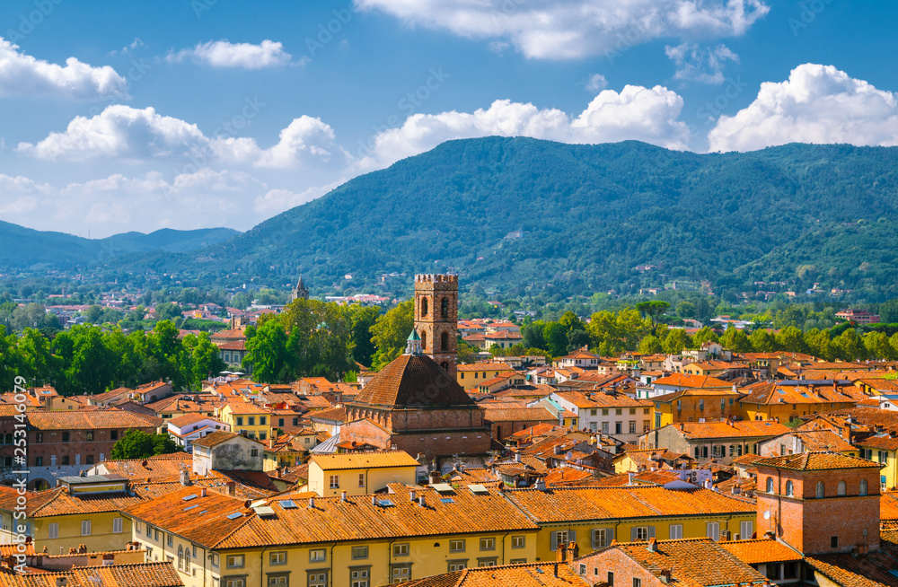 Aerial top panoramic view of Chiesa dei Santi Giovanni e Reparata catholic church in historical centre medieval town Lucca with terracotta tiled roofs and mountain range background, Tuscany, Italy
