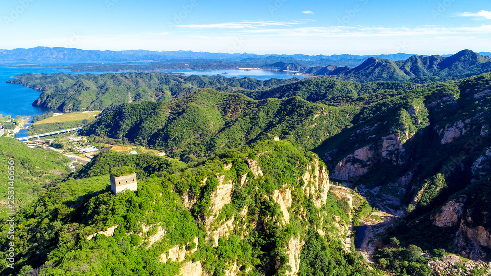 Obraz premium Aerial view of mountain with water reservoir on the background. Mountain peak with beautiful blue sky and green forest. Landscape of mountain in natural reserve park. Miyun, Beijing, China.