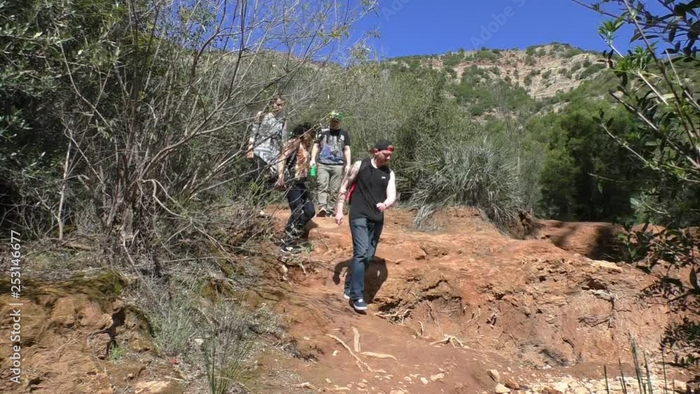 Group of four tourists hiking in a hilly area in Morocco on a hot day Group of four tourists hiking in a hilly area in Morocco on a hot day