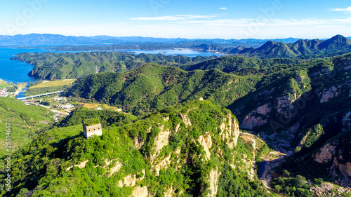 Aerial view of mountain with water reservoir  on the background. Mountain peak with beautiful blue sky and green forest. Landscape of mountain in natural reserve park. Miyun, Beijing, China. photo