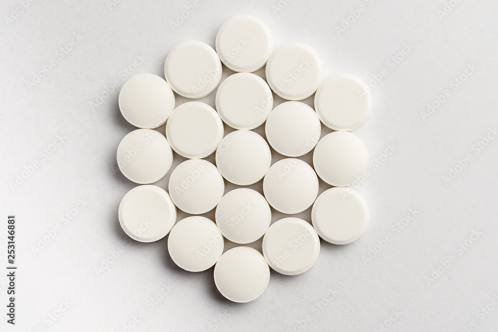 Close up of a group of white pills on white background, beautifully arranged, top view