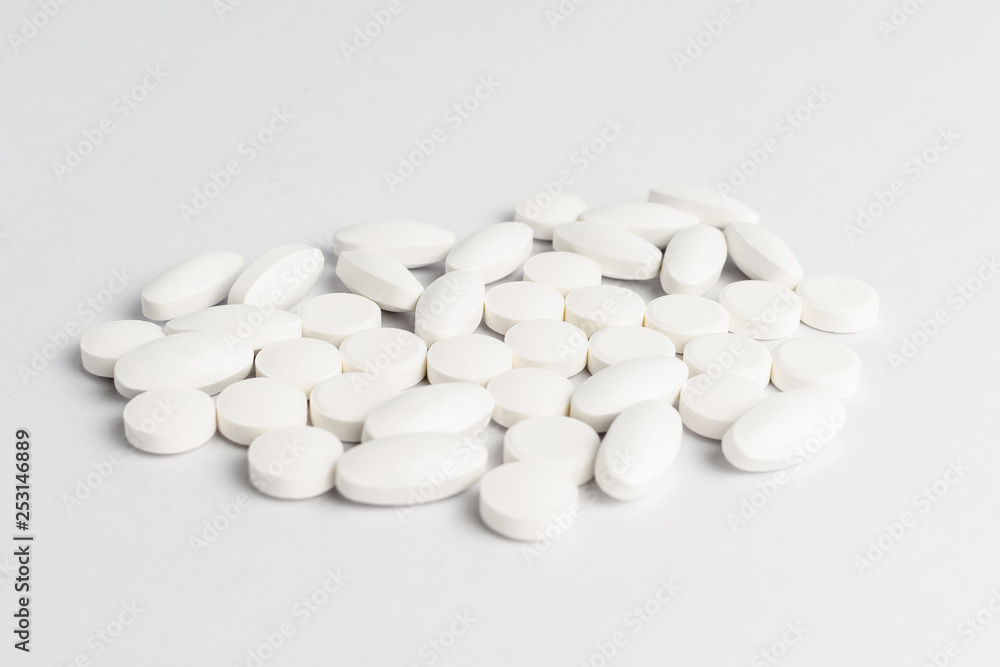 Close up of a group of white pills on white background, in random order Close up of a group of white pills on white background, in random order