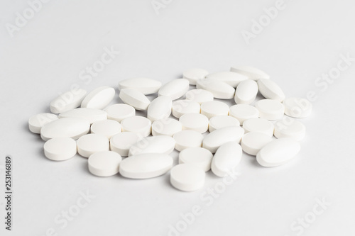 Close up of a group of white pills on white background, in random order