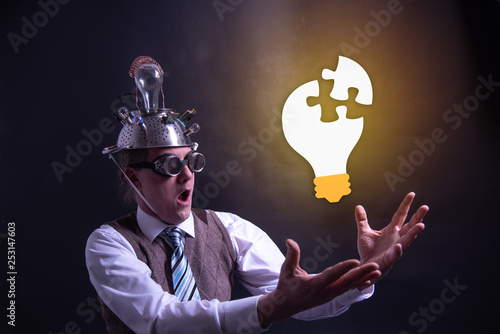 Funny nerd or geek with aluminium hat looking to light bulb having an idea photo