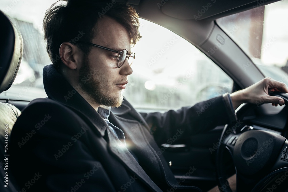 man hipster with a beard in glasses a driver of a modern car in salty weather. man hipster with a beard in glasses a driver of a modern car in salty weather.