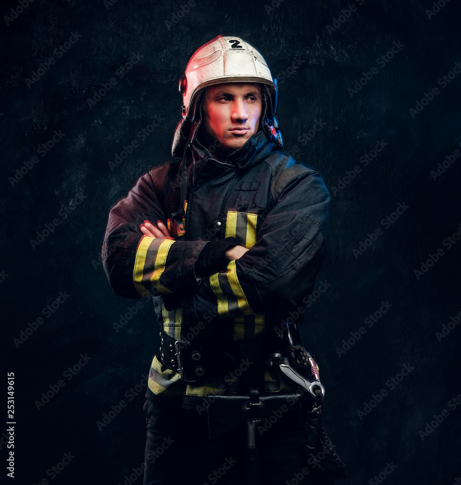 Manly firefighter in helmet looks sideways in studio on black background Manly firefighter in helmet looks sideways in studio on black background