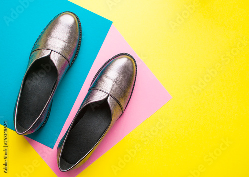 Pair of sparkly female shoes on yellow, pink and blue background with copyspace. Flat lay style.