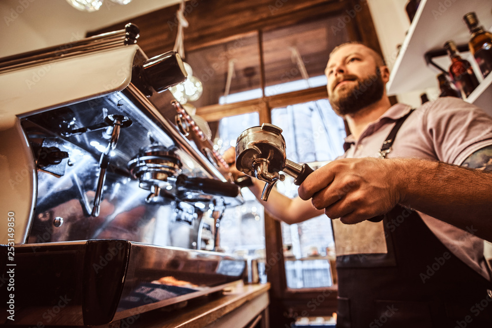 Low angle photo of a barista holding a portafilter, working in the coffee shop or restaurant