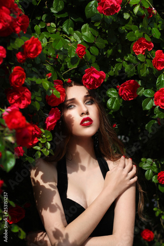 Portrait of beautiful young woman in the rose garden, spring time, rose flowers blossoms.