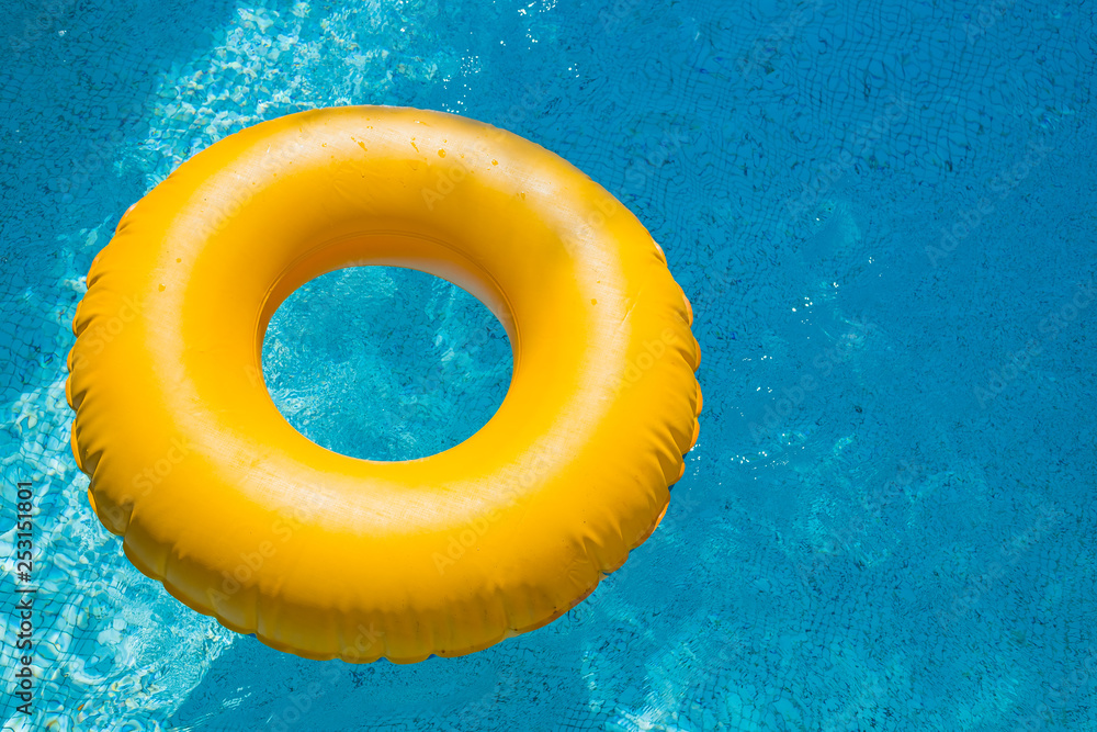 floating ring on blue water swimpool with waves reflecting in the summer  sun. Lazy river.Water pool with yellow pool float ring.Summer vacation or  trip safety item. Top view swimming circles.rubber Stock Photo