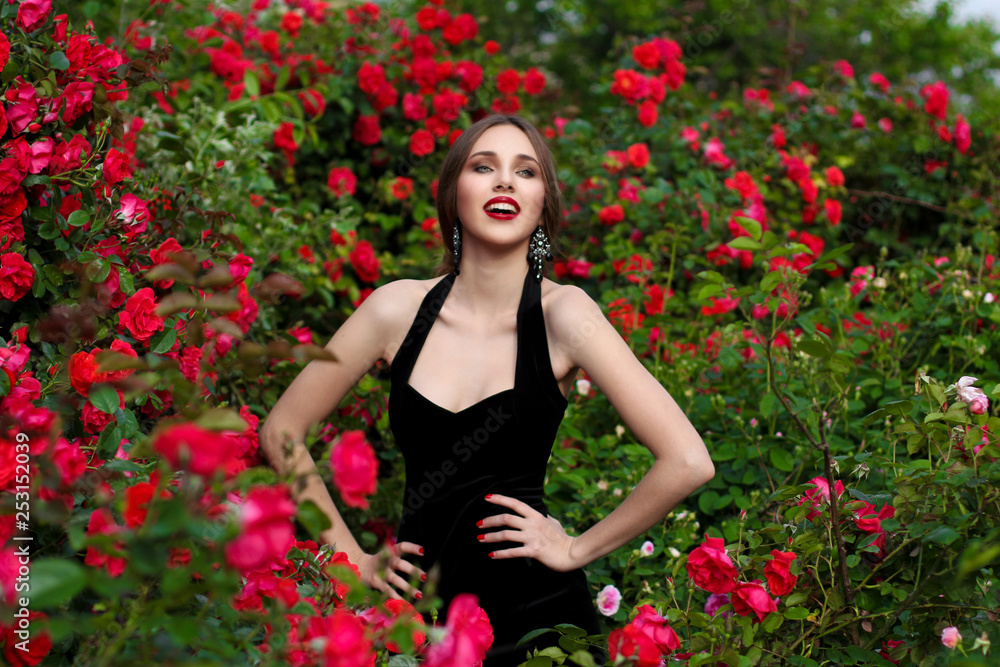 Portrait of  beautiful young woman in the rose garden, spring time, rose flowers blossoms.