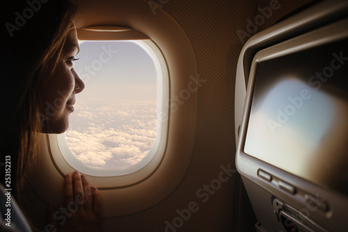 Woman looking through window in airplane 