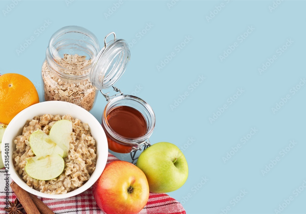 Raw oats in bowl and fruit salad, apples on the wooden table Raw oats in bowl and fruit salad, apples on the wooden table